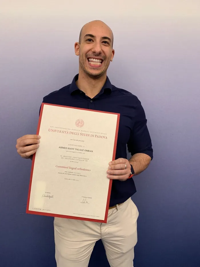 Dr Omran holding his lingual orthodontics master's diploma from the University of Padua